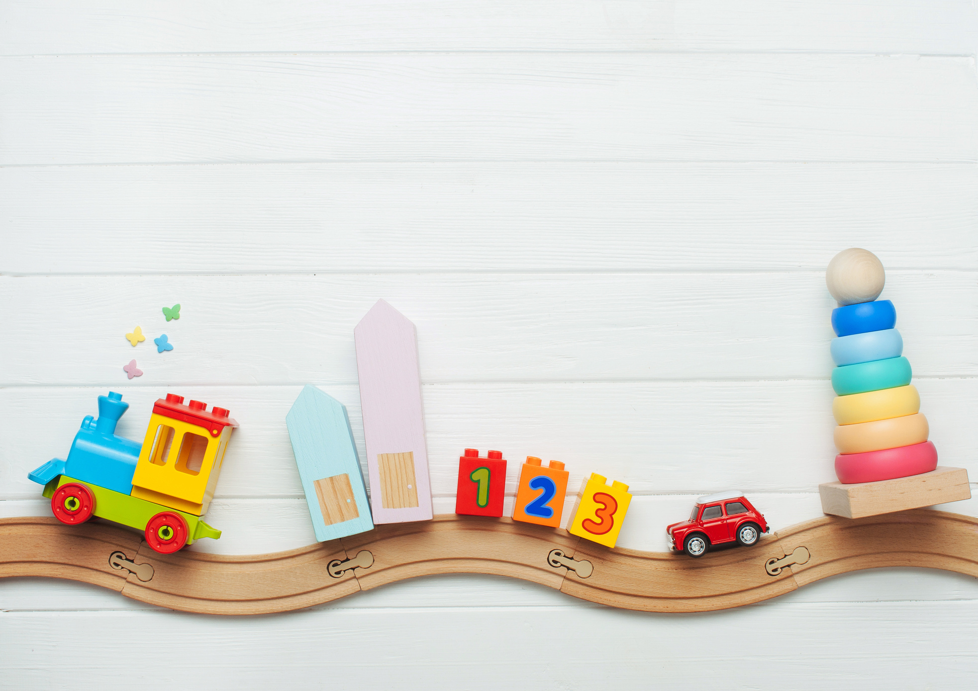 Kids toys on toy wooden railway on white background