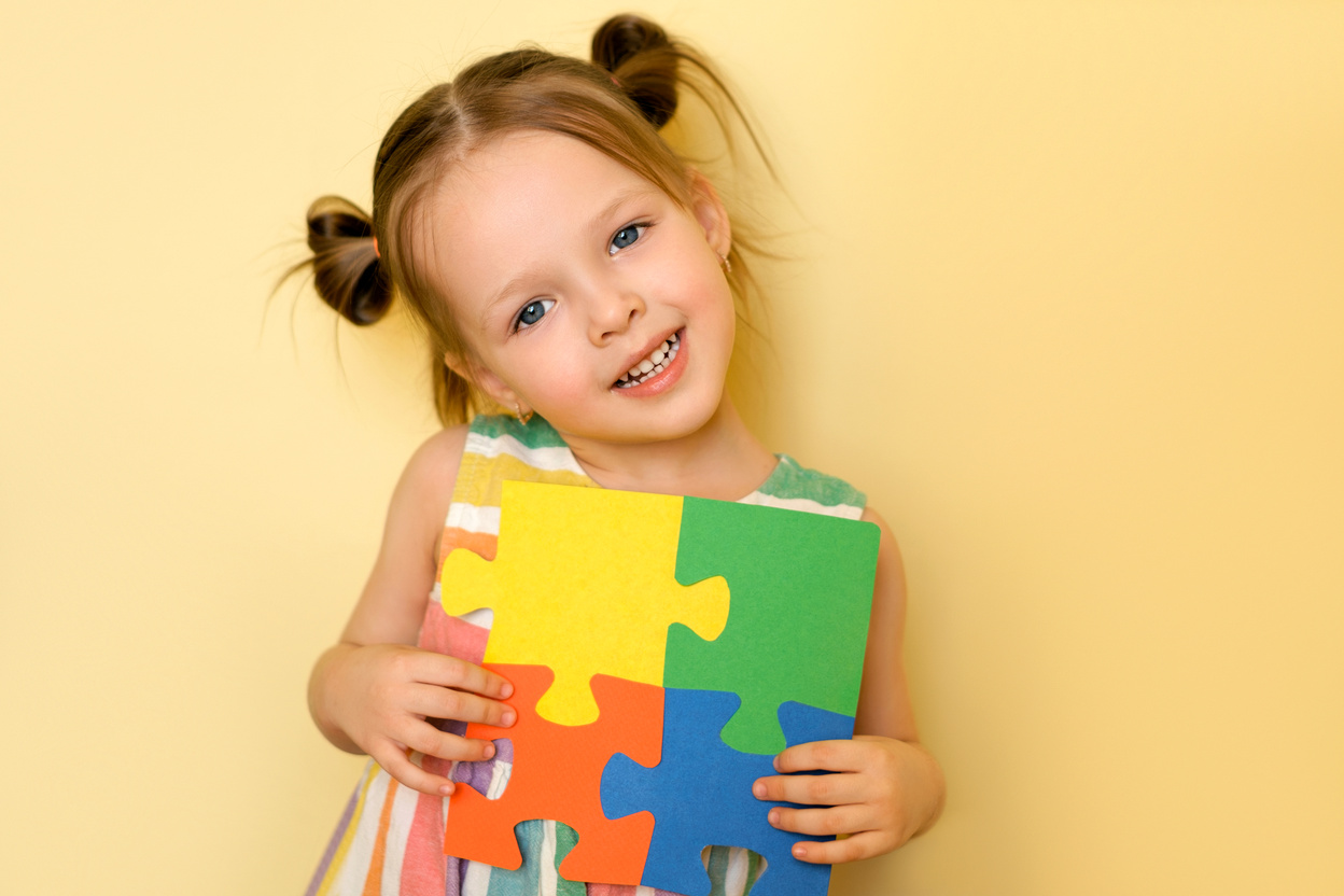 Girl shows the pieces of puzzles, support for people with au